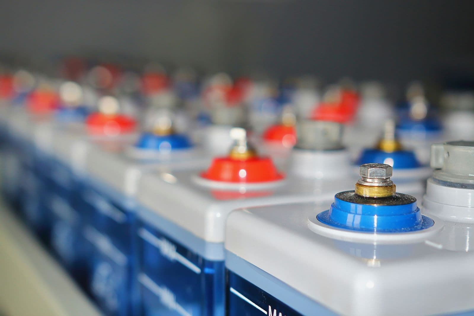 A row of industrial batteries with red and blue terminal covers, close up in a backup power system.